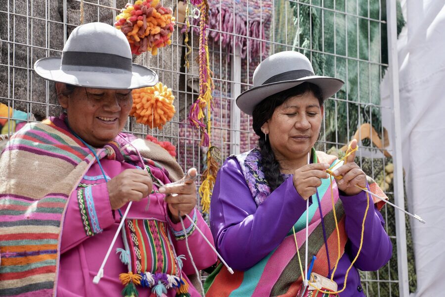 Dos tejedoras con sombrero andino trabajando juntas