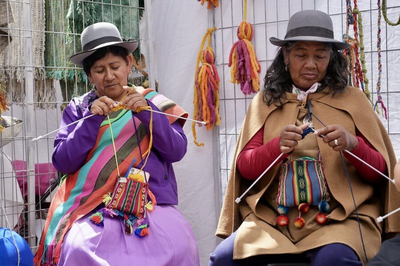 Dos tejedoras con vestimenta tradicional andina tejiendo en la feria del Festival de la Lana en San Pedro de Atacama